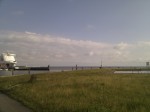 Gras im Vordergrund Meer und Horizont im Hintergrund und links eine Fähre