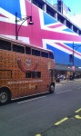 Bus in front behind big britishflag like house wall